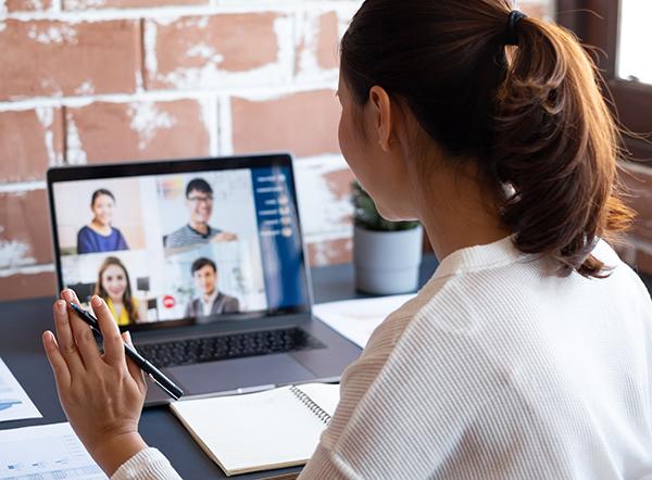 Woman waving to laptopscreen on webinar training